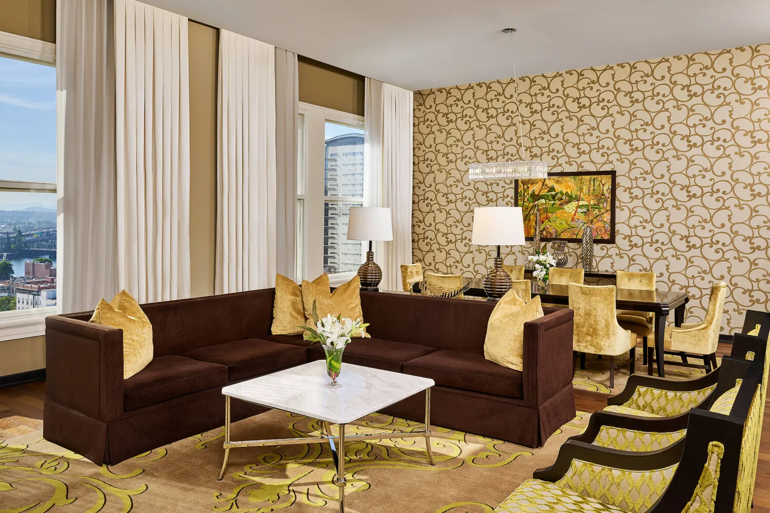 Luxurious hotel suite living area with brown sectional sofa and city view