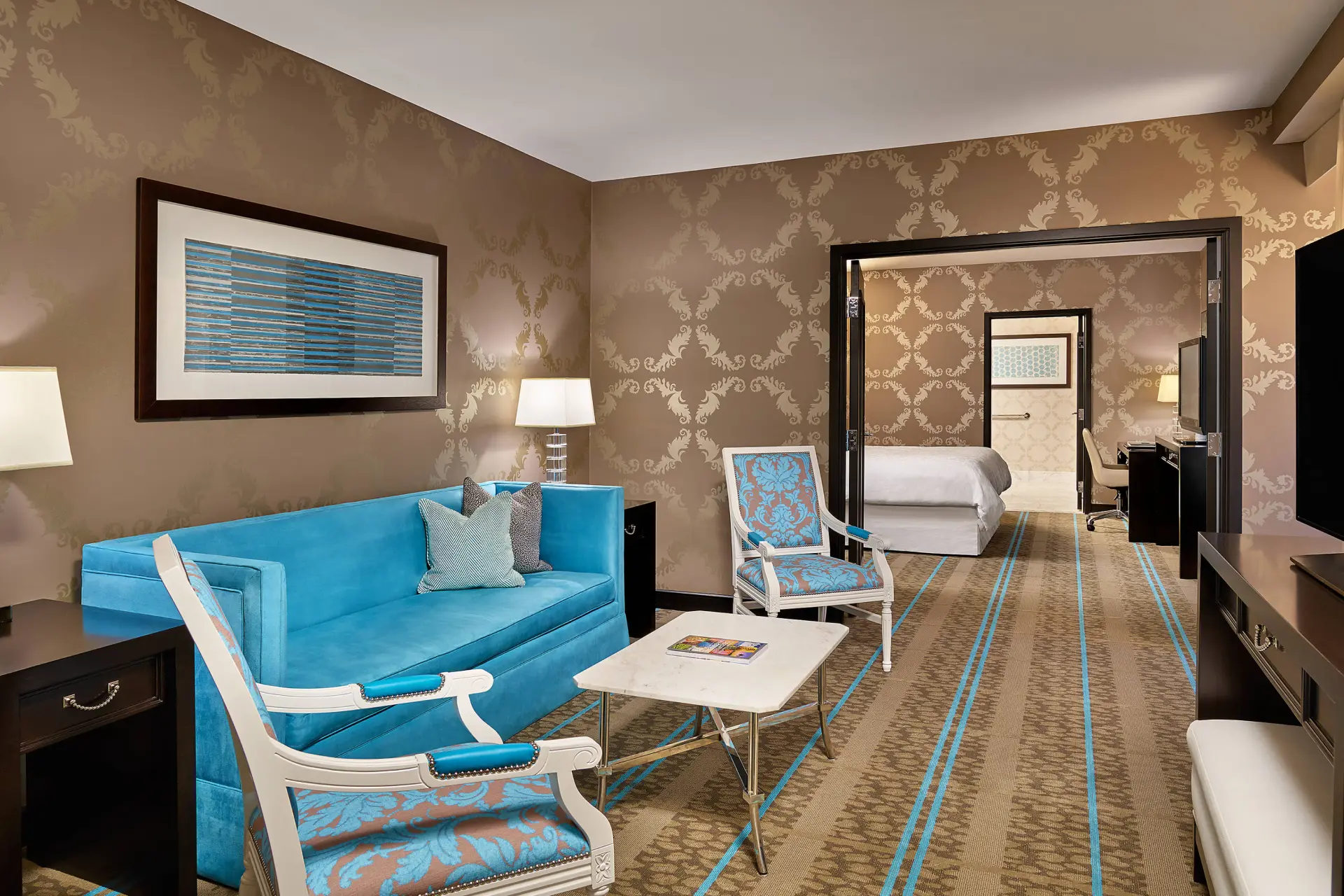 Hotel suite living area with blue sofa and patterned wallpaper