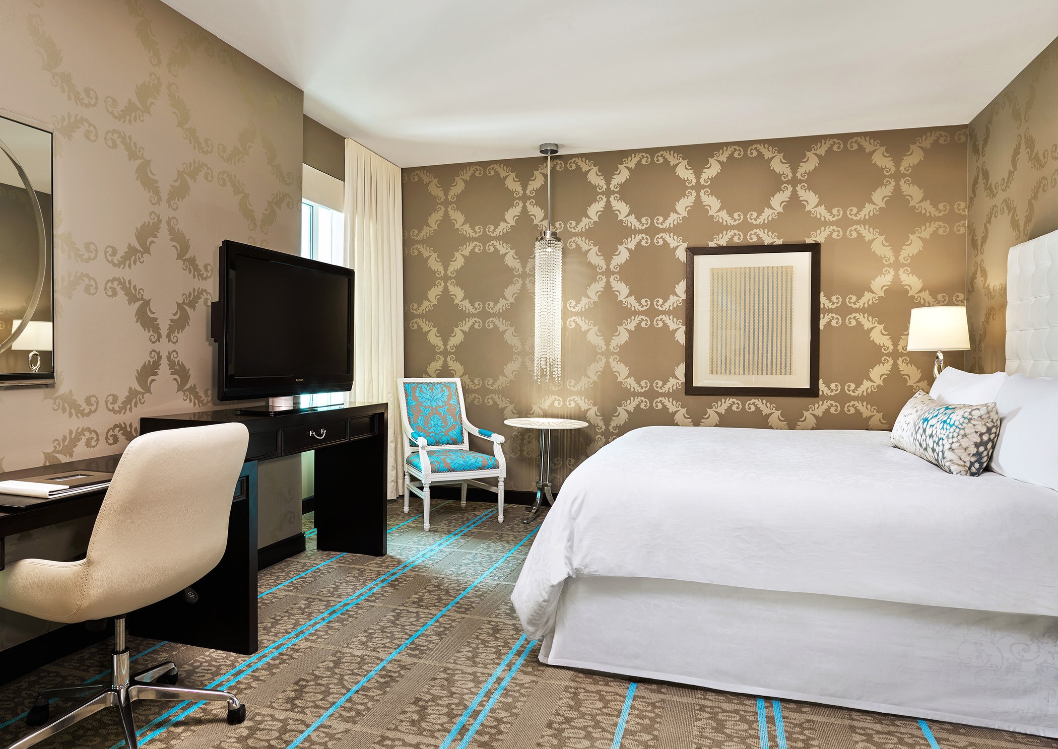 Hotel room with patterned wallpaper, king bed, and blue accents