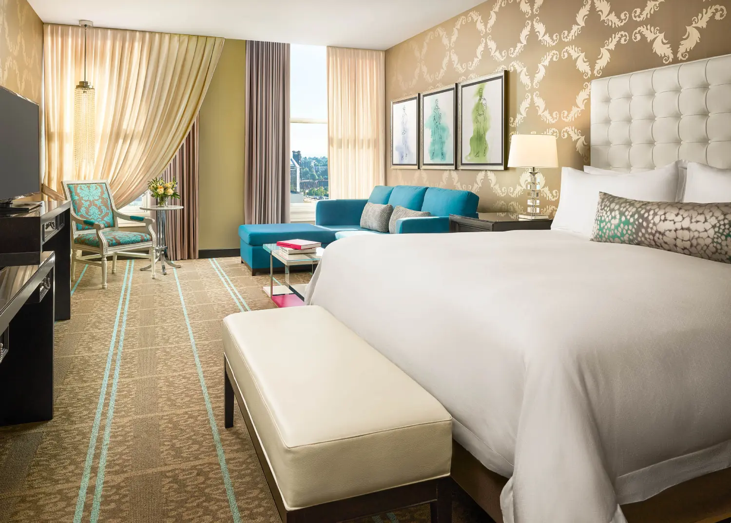 Luxurious hotel room with king bed, teal sofa, and patterned wallpaper