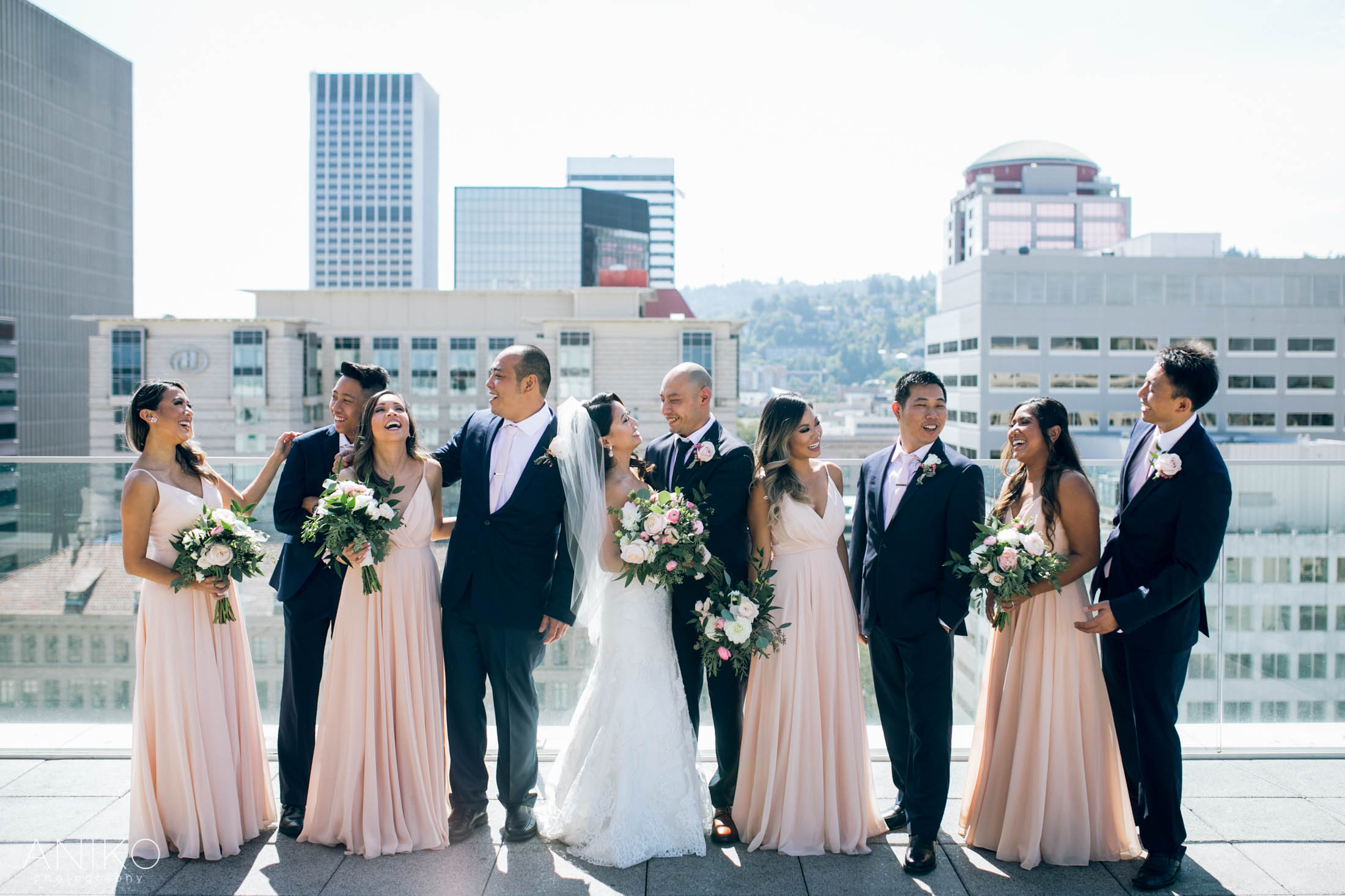 Wedding party posing on a rooftop terrace with a city skyline background