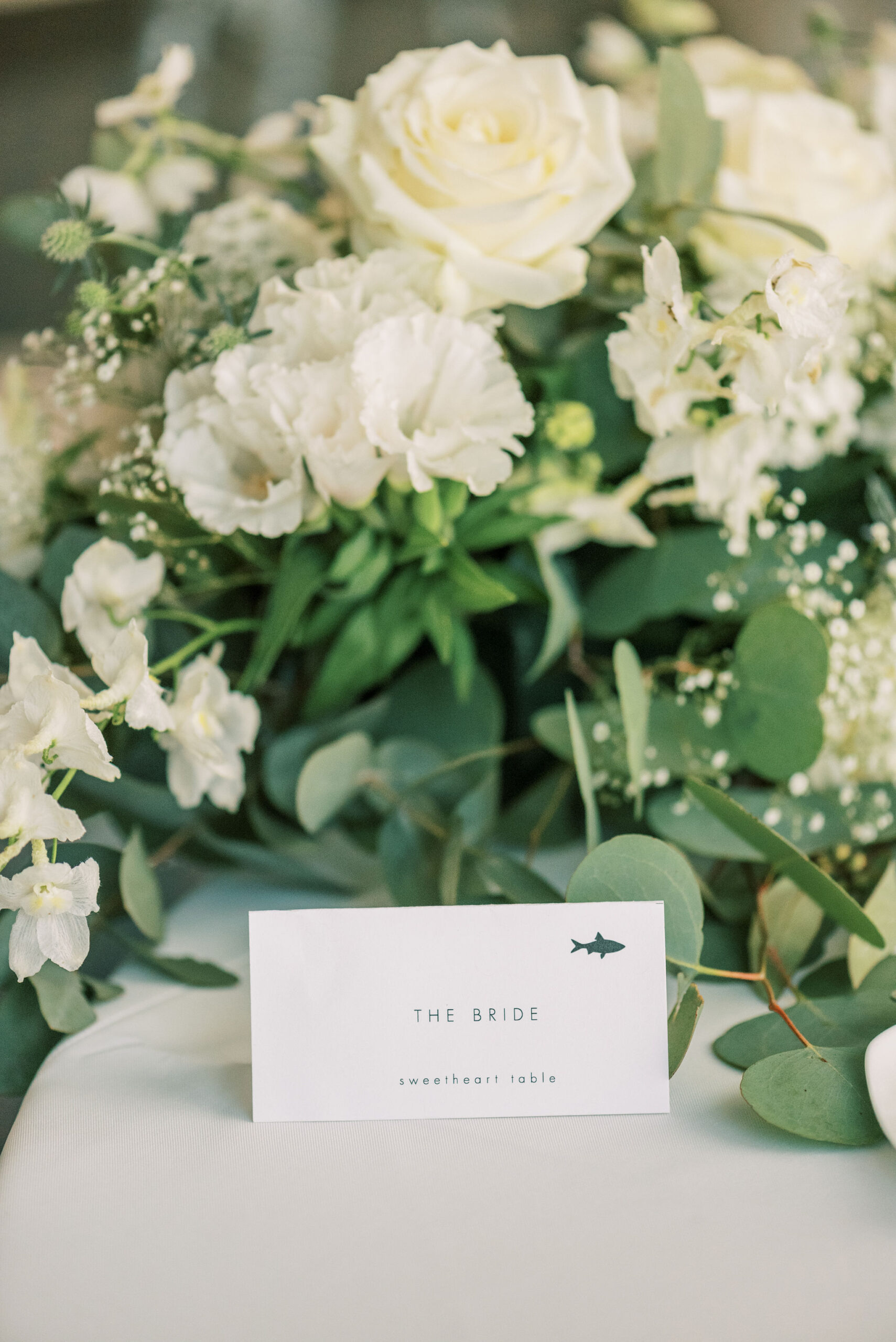 Bride's sweetheart table card with white floral arrangement