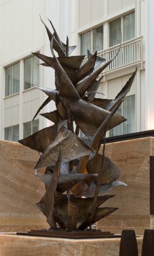 Abstract dark metal sculpture with sharp, jagged shapes on a stone base.