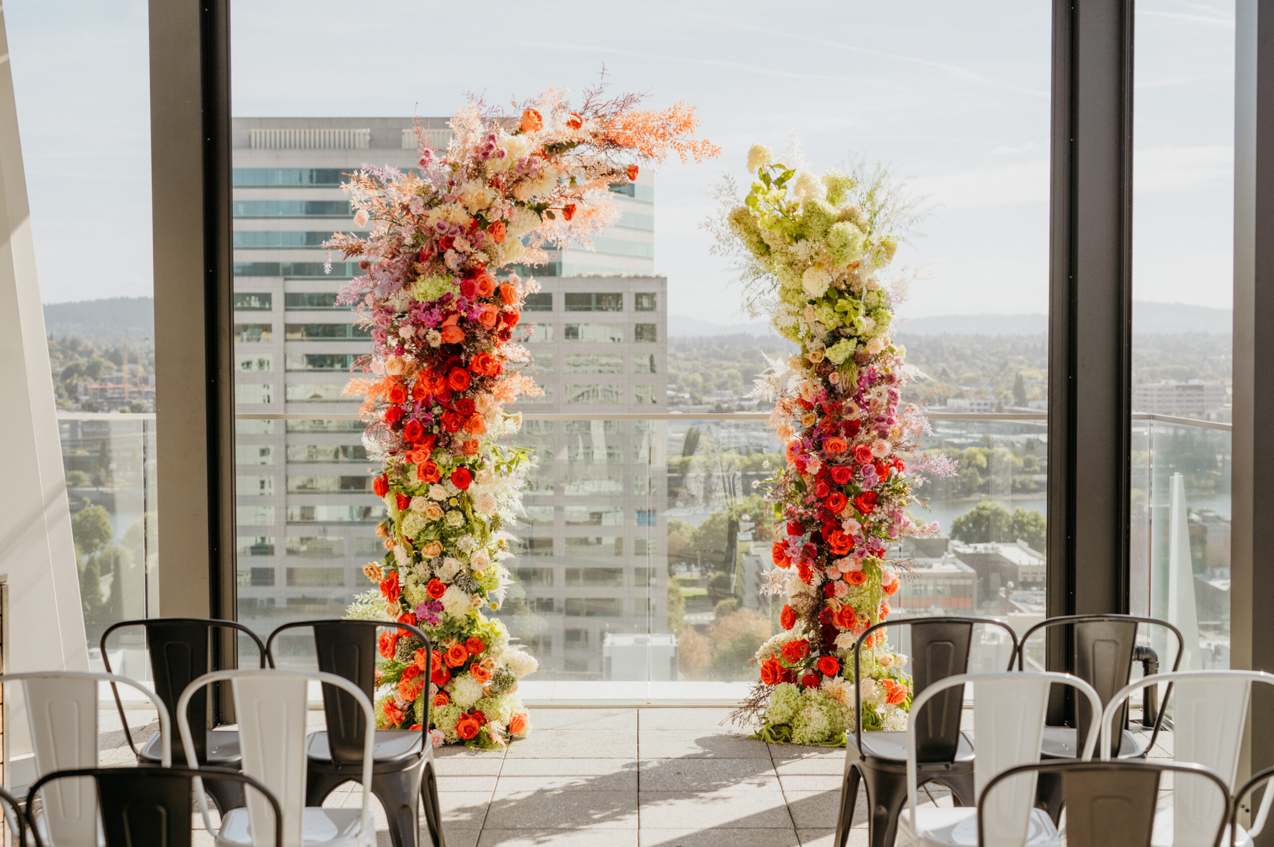 Elegant floral arches with vibrant red and white blooms framing a city view for a wedding ceremony at The Nines.
