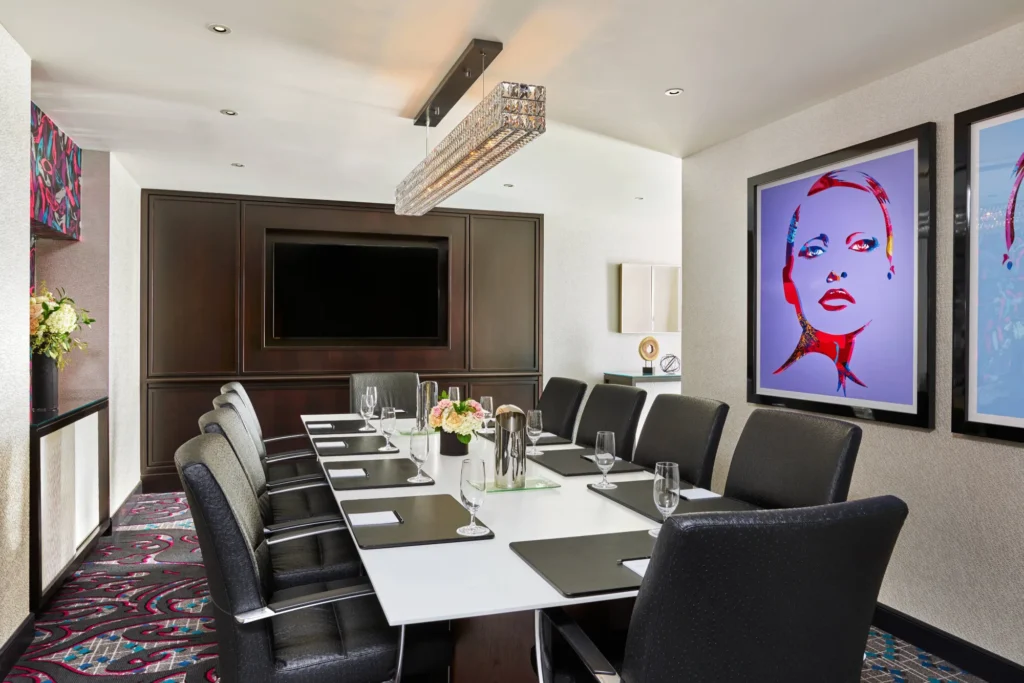 Modern conference room with long table, black chairs, and pop art portraits