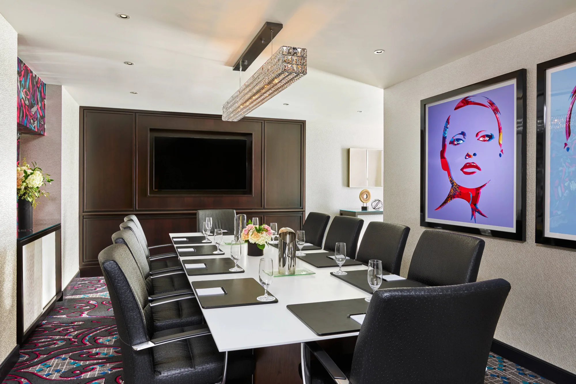 Modern conference room with long table, black chairs, and pop art portraits